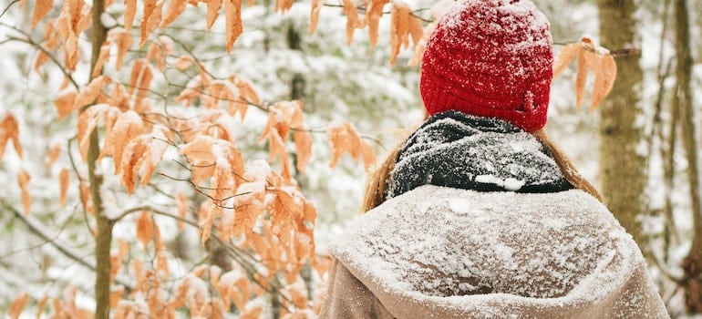 A woman in a winter gear looking into the distance as she wonders about how to adjust to colder climate..