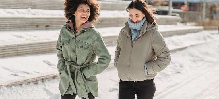 Two girls walking together during cold weather.