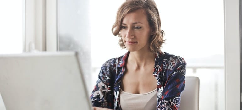 A woman doing research on her laptop for a new job outside of Florida.