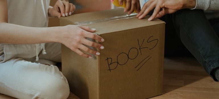 Two people packing and labelling moving boxes.