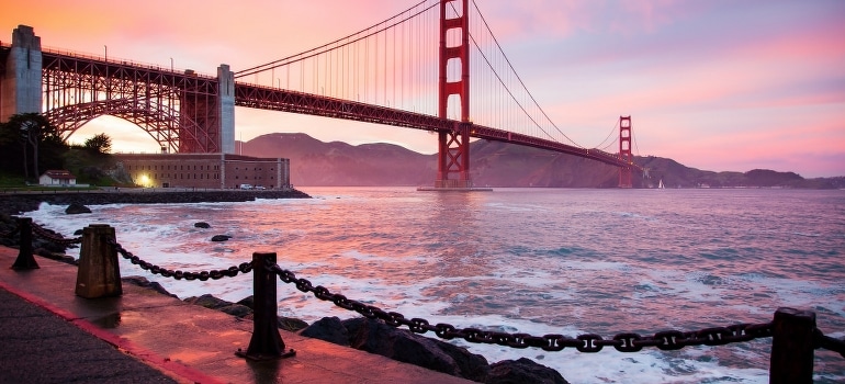 Sunlit beach with palm trees and the bridge in San Francisco highlights the cultural differences between Miami and San Francisco.