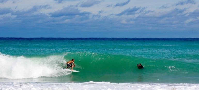 Two men surfing at sea waves and talking about tips for young professionals moving to Florida cities