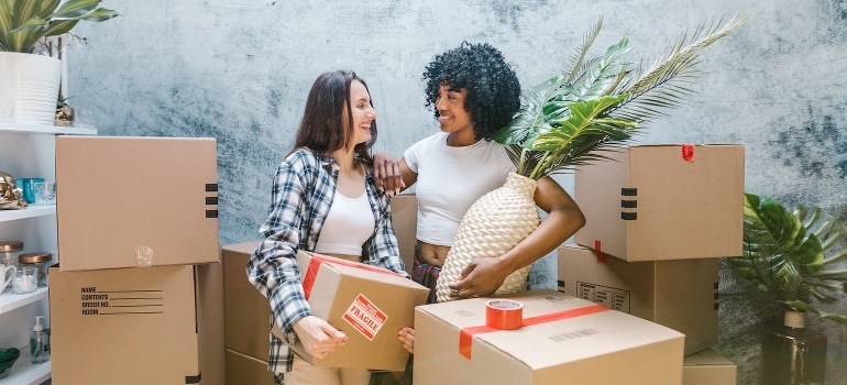 Two women surrounded by boxes talking about tips for young professionals moving to Florida cities