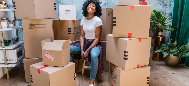 A woman sitting beside cardboard boxes.