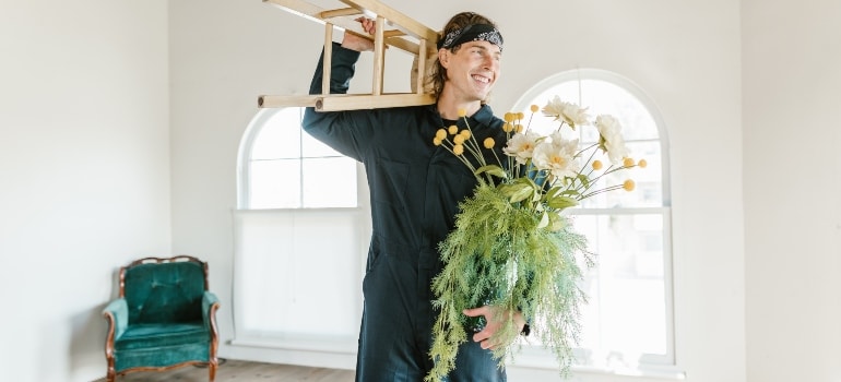 a mover carrying a chair and a plant 
