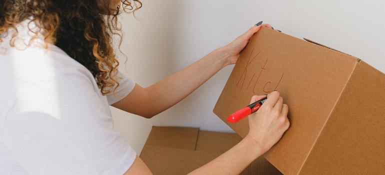 A woman labeling a box to pack for a move in 3 days.