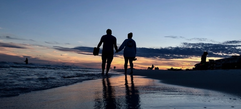Two people walking on the seashore in Miramar Beach. 
