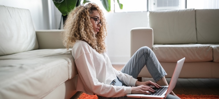 A young woman is using a laptop to prepare for moving to Fort Lauderdale this summer.