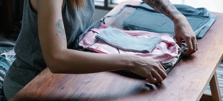 A person packing clothes following seasonal storage solutions.