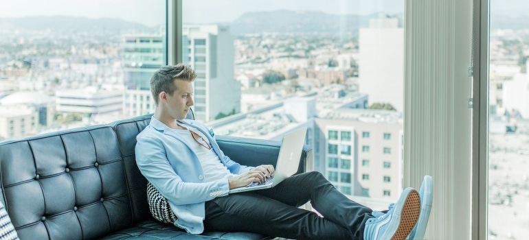 A man sitting on a sofa and using a laptop
