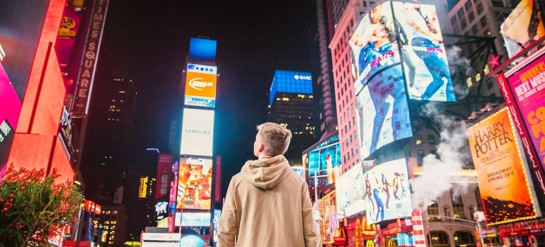 A young man standing and looking at Times Square after moving to New York from Florida