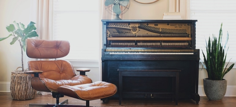 Black piano near the leather chair
