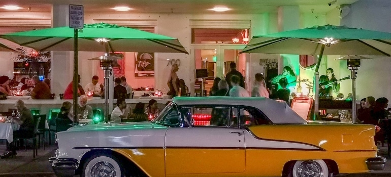 A yellow and white car parked beside the place where people exploring the best nightlife in Florida.