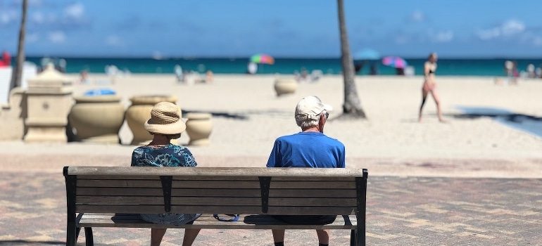 Seniors sitting on the wooden bench and talking about senior activities in Boca Raton.