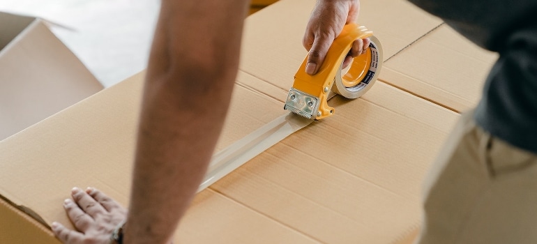 A man packing the box with scotch packing tape