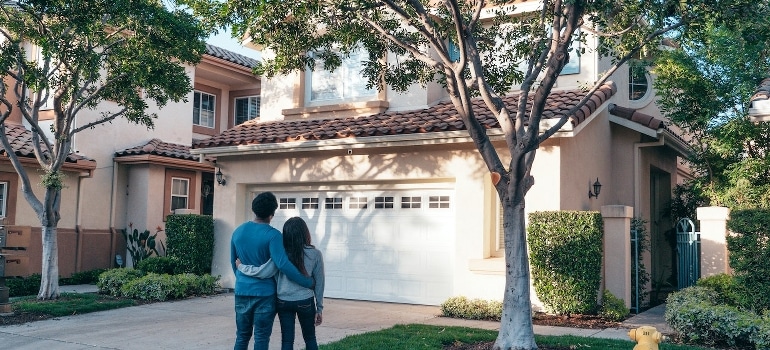 A couple standing in front of their new home after they have hired long distance movers Boca Raton is happy to offer.