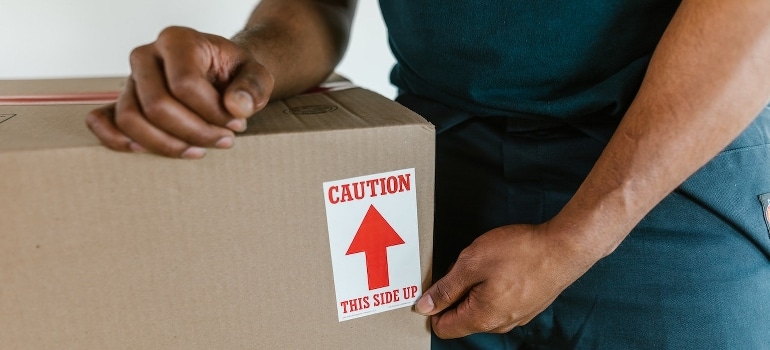 A person holding a labeled cardboard box