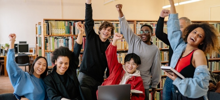 A group of students smiling at the library after moving to Highland Beach