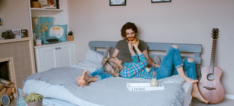 A man and woman who get tired of living in Boca Raton lying on bed