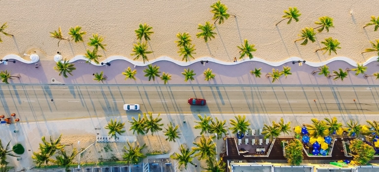 Aerial view of the two vehicles on the concrete road while they are moving to Hallandale Beach from Boca Raton. 