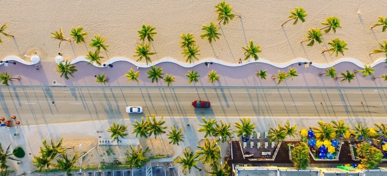 Aerial view of the two vehicles on the concrete road while they are moving to Hallandale Beach from Boca Raton.