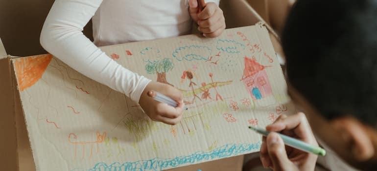 A kid drawing on a moving box