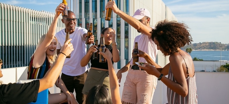 Joyful friends toasting with beer and trying to deal with stress when moving to Miami. 