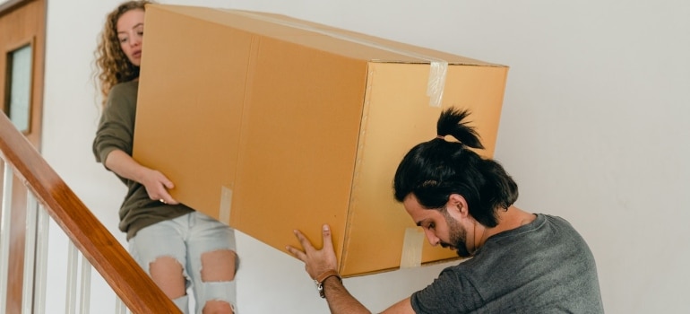 couple carrying a box and applying safety measures when dealing with extra heavy items