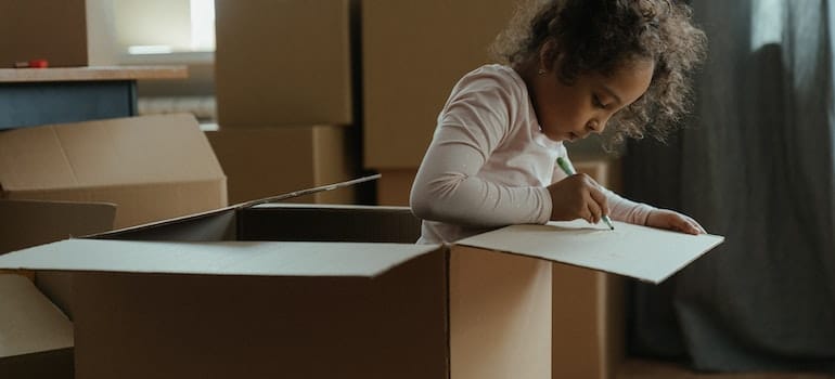 A kid drawing on the moving box 