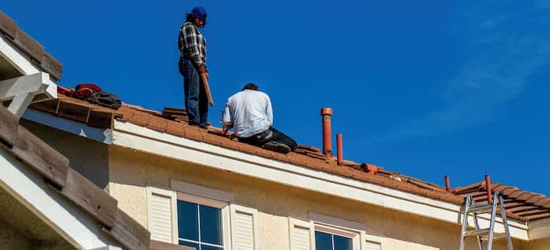 Two people fixing roof in order to prepare your Boca Raton home for hurricane season