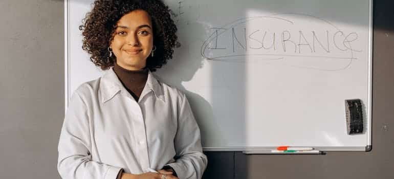 A woman standing next to the board written insurance on it