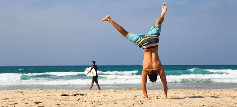 A man doing a hand stand on the beach