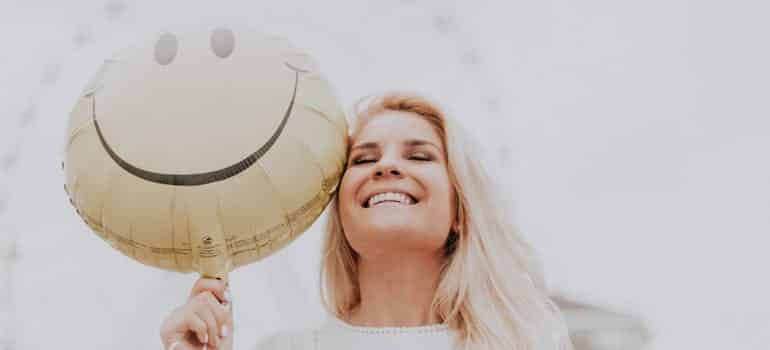 A happy woman holding a smiley balloon