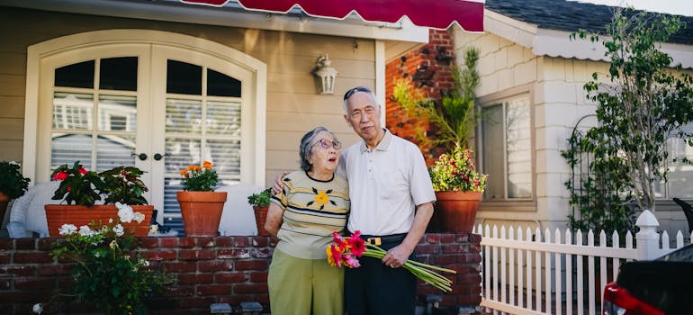 A senior couple in front of the house