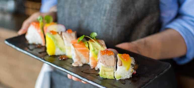 A person holding a plate of sushi